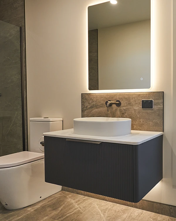 Warmly lit bathroom featuring a floating vanity and back-lit mirror in Bay of Plenty bathroom after renovation by Home Improvement Specialist