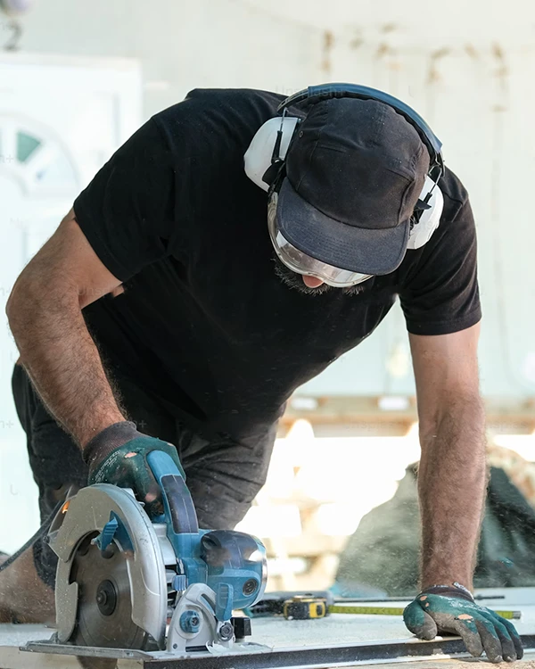 Builder using saw to cut timber for home alteration project in Tauranga