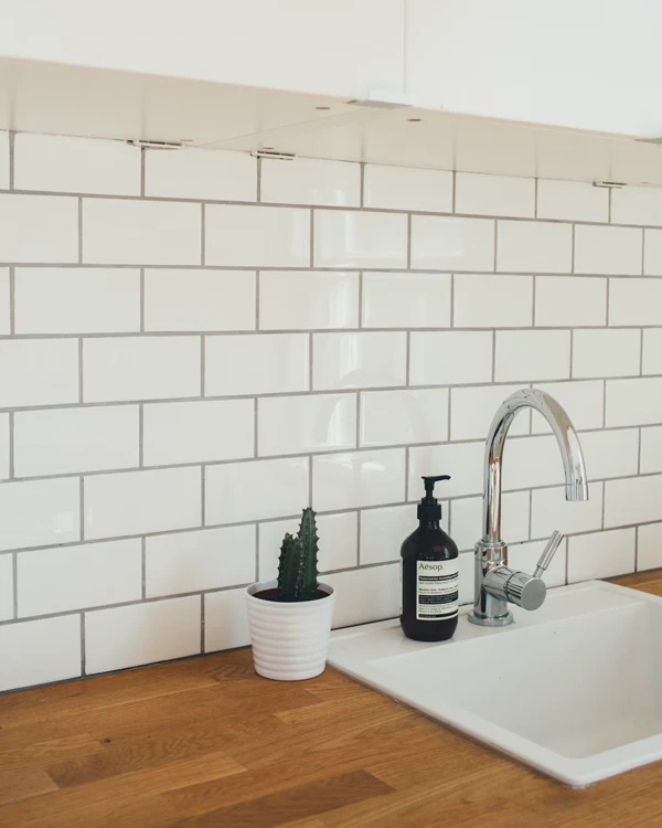 Kitchen splashback tiled with glossy white tiles. Wooden kitchen countertop. Work undertaken by Home Improvement Specialist Tauranga