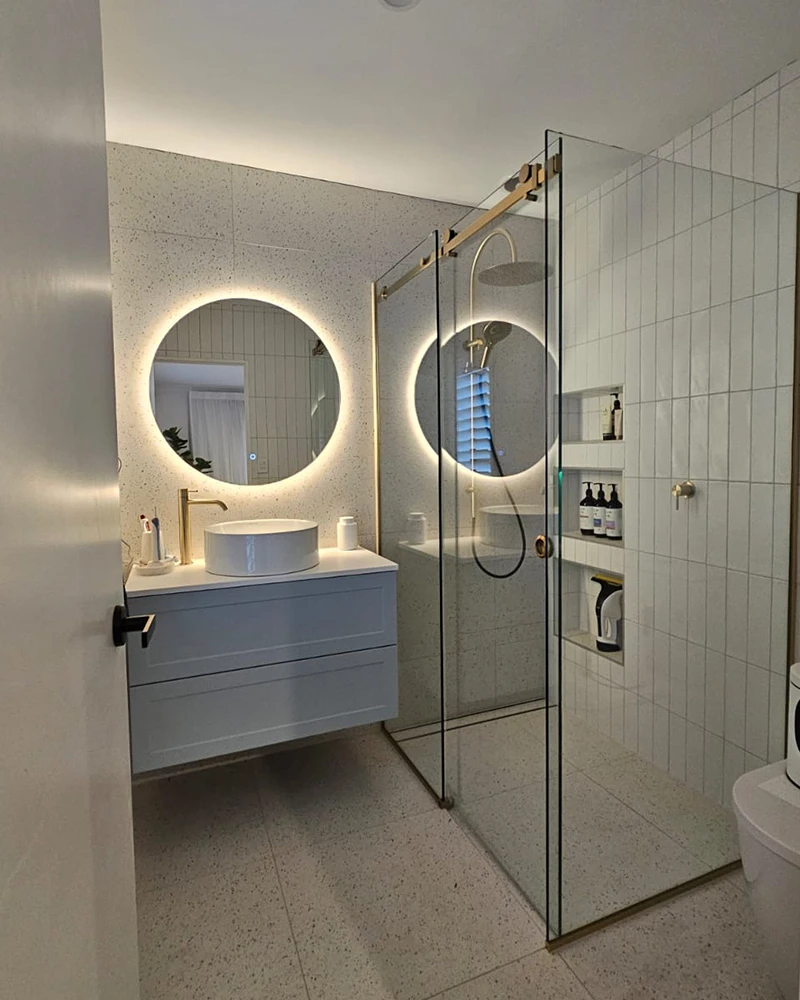 Backlit mirror in bathroom with shower and vanity