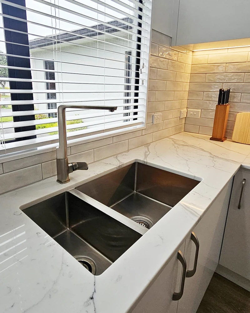 Close up photos of stainless steel kitchen sink install with modern grey metal tapware